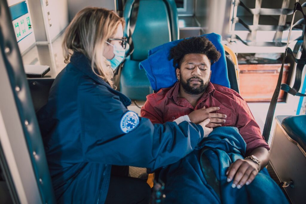 A paramedic attends to an injured man in an ambulance, ensuring his safety and comfort.
