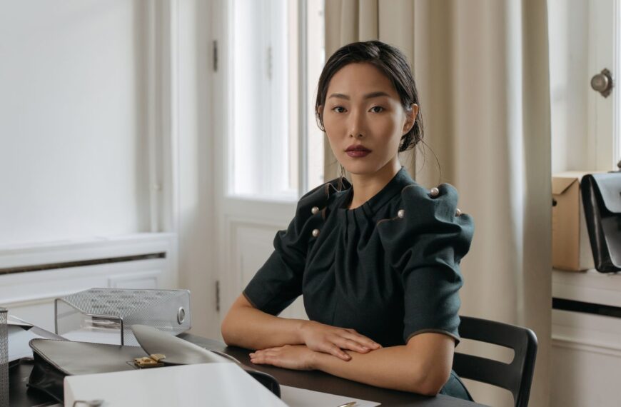 Elegant Asian businesswoman sitting confidently in a modern office setting.