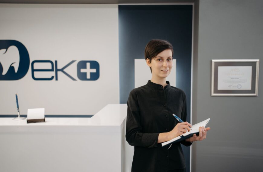 Smiling woman holding a notebook at a modern dentist office reception area.