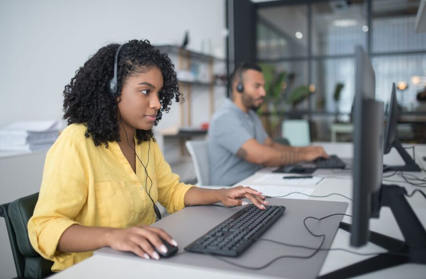 Two customer service agents working with headsets in a modern office setting.
