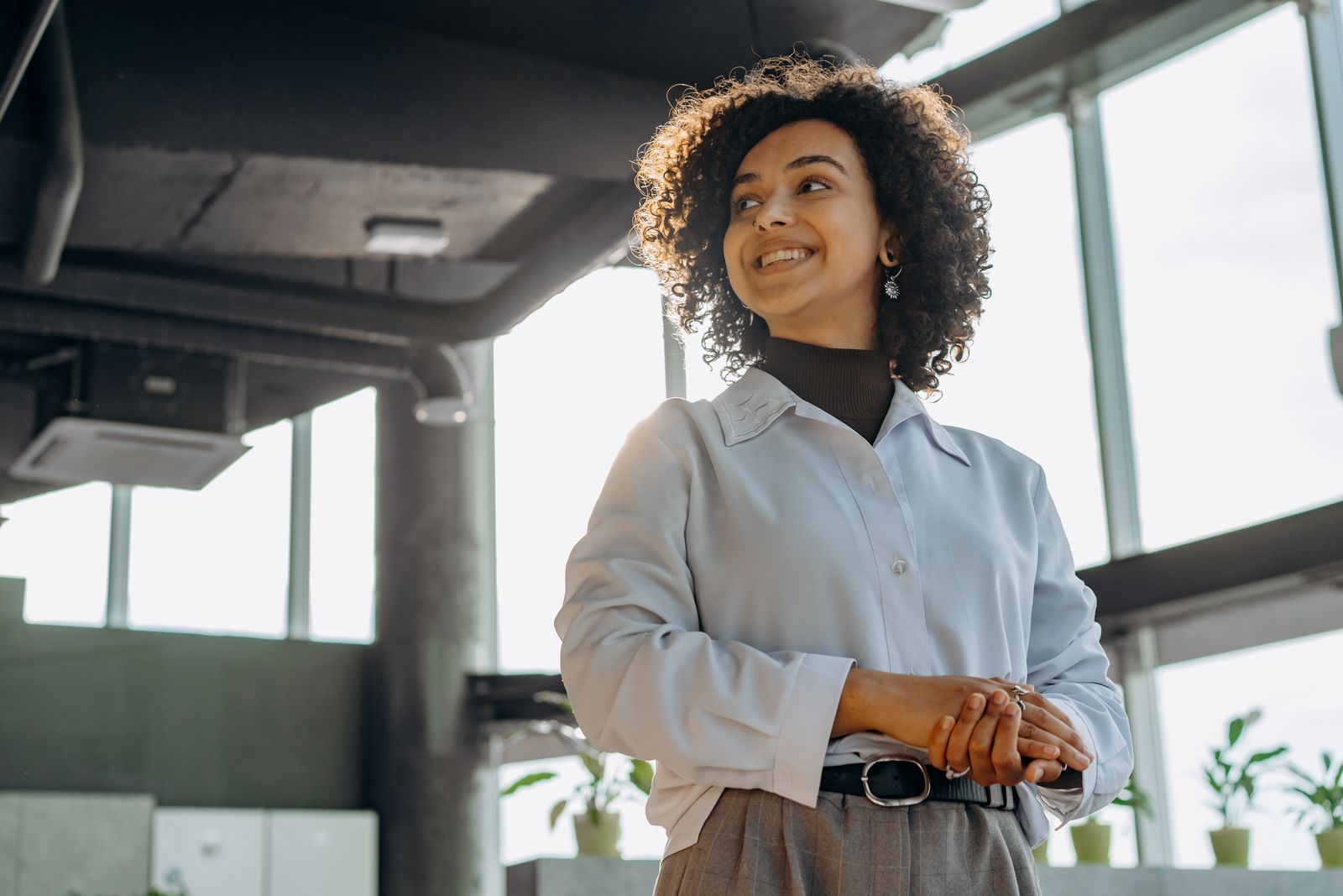 Confident businesswoman with curly hair in a bright, modern office environment.