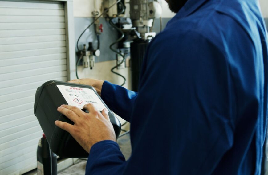 Mechanic using diagnostic tool to inspect vehicle in an automotive workshop.