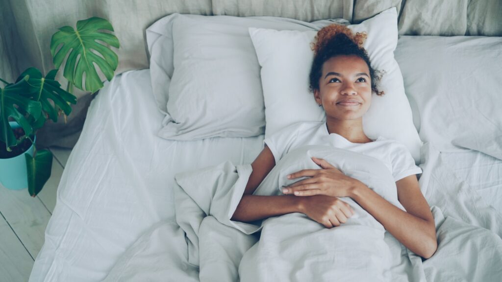 Young woman lying in a white bed