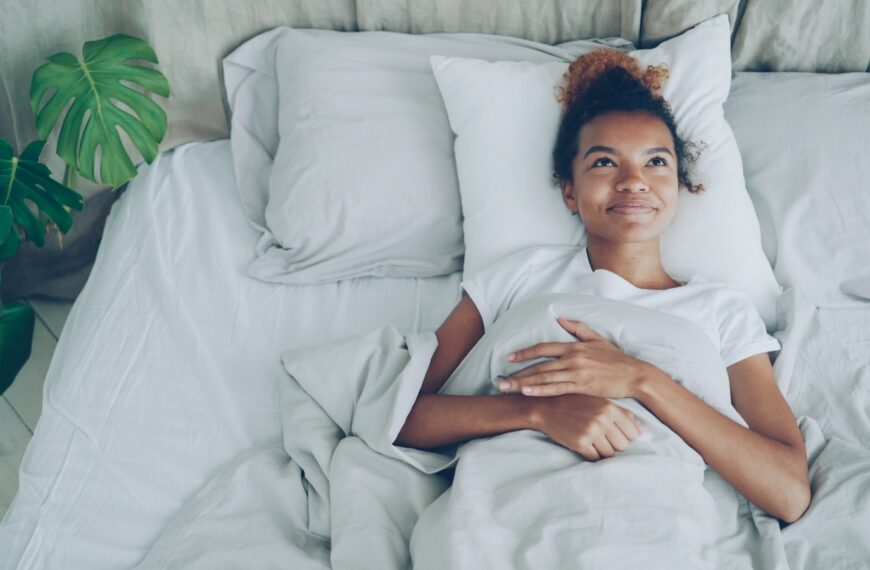 Young woman lying in a white bed