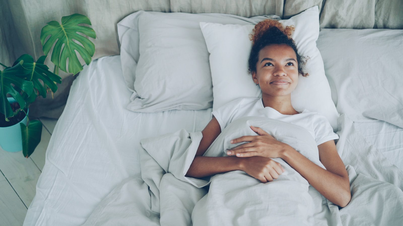 Young woman lying in a white bed