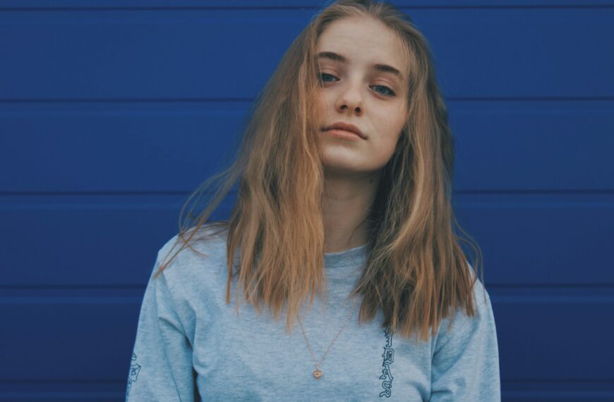 a woman with long hair standing in front of a blue wall