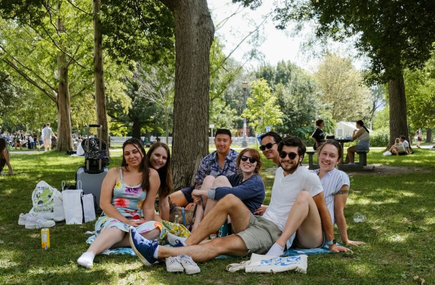 a group of people sitting on top of a lush green park
