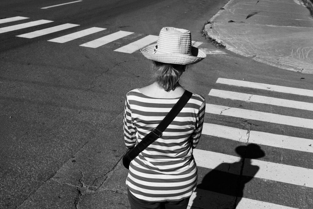 Woman in striped shirt and hat at crosswalk