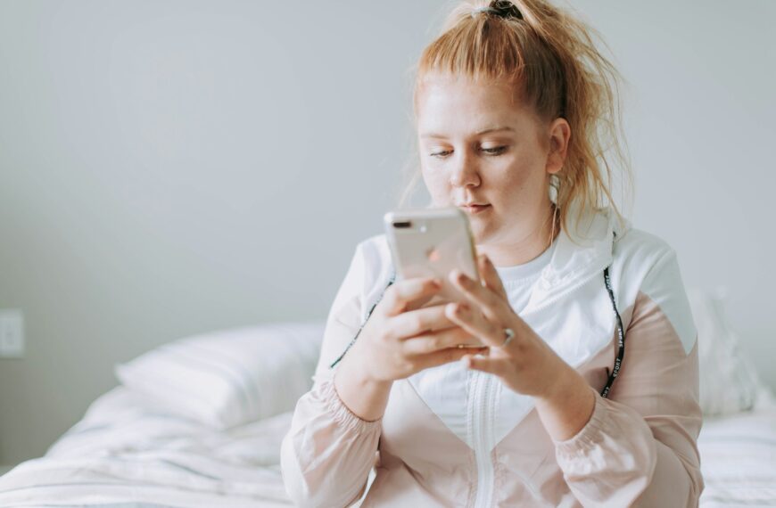 woman sitting on bed while using gold turned 8 Plus