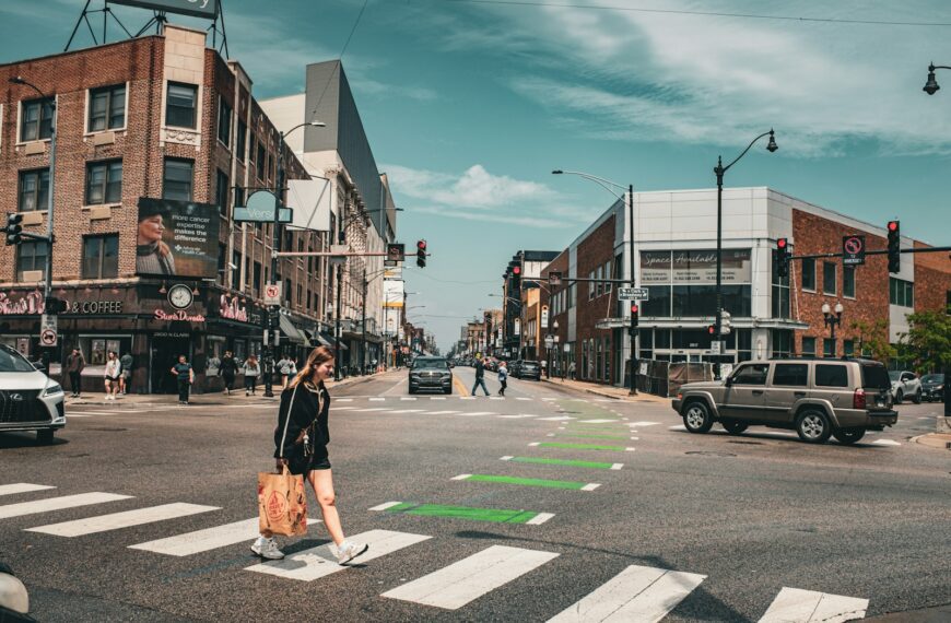A woman crosses a busy city street at a crosswalk.
