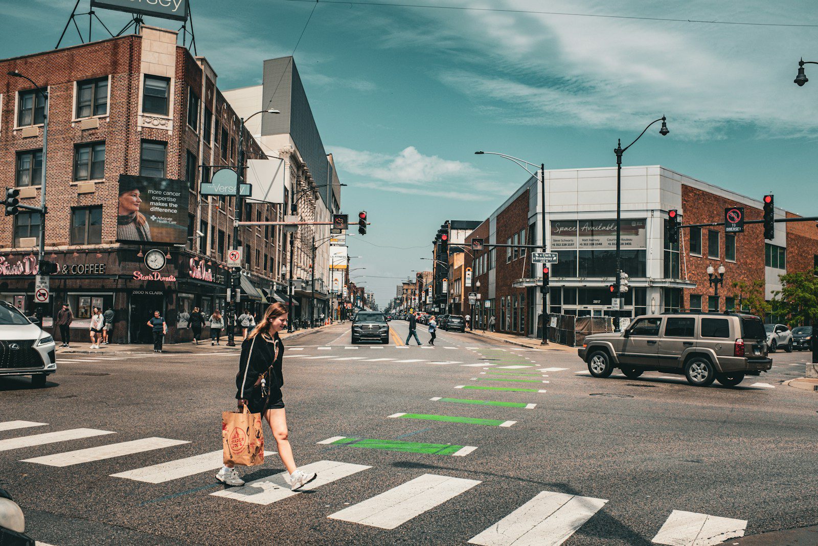 A woman crosses a busy city street at a crosswalk.