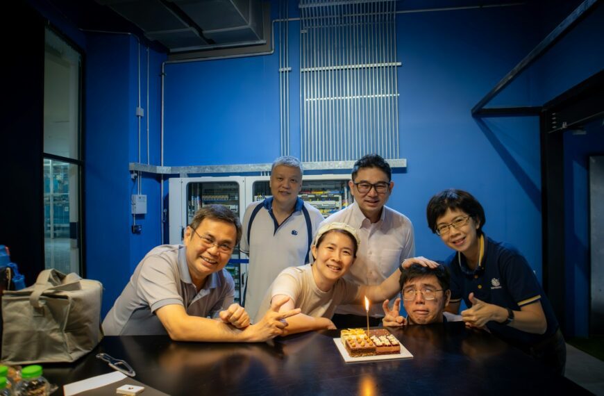 A group of people standing around a table with a cake