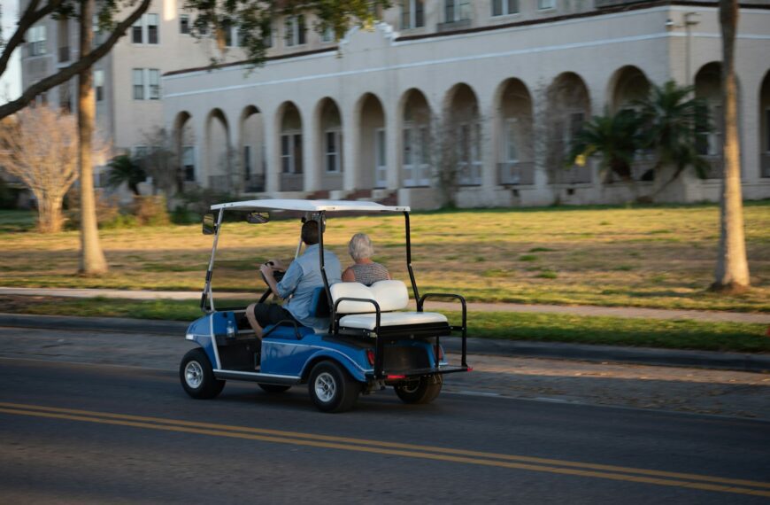 two people riding a golf cart down a street