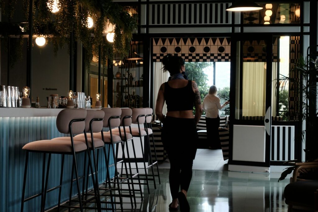 Woman walks into a stylish bar with stools.