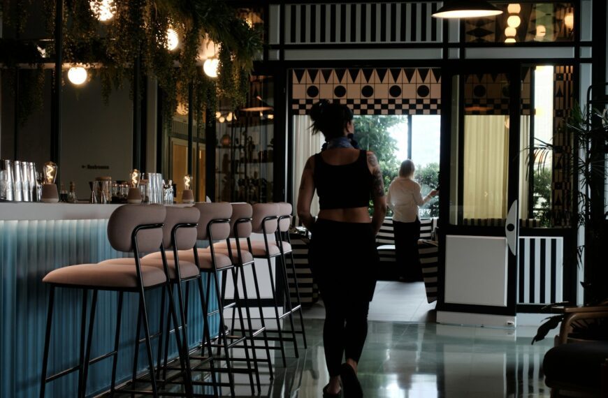 Woman walks into a stylish bar with stools.
