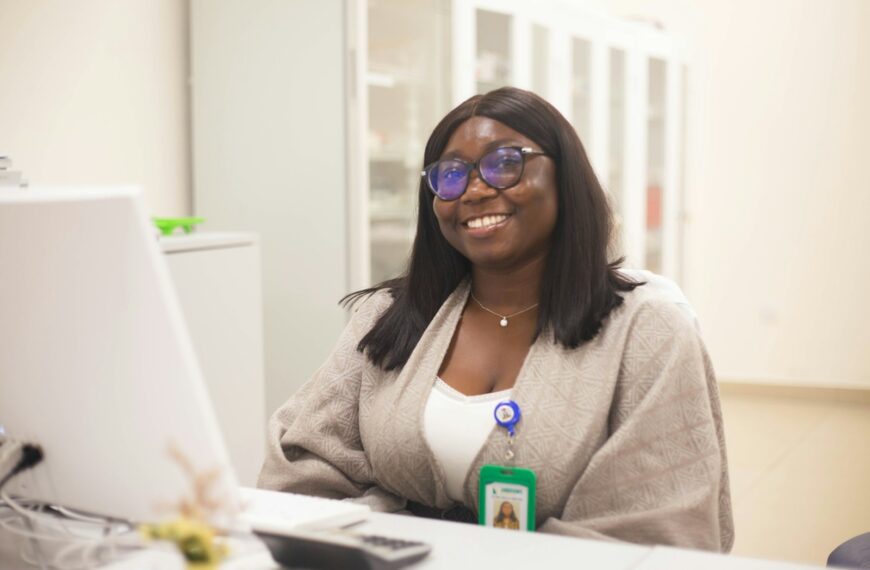 A smiling woman sits behind a desk.