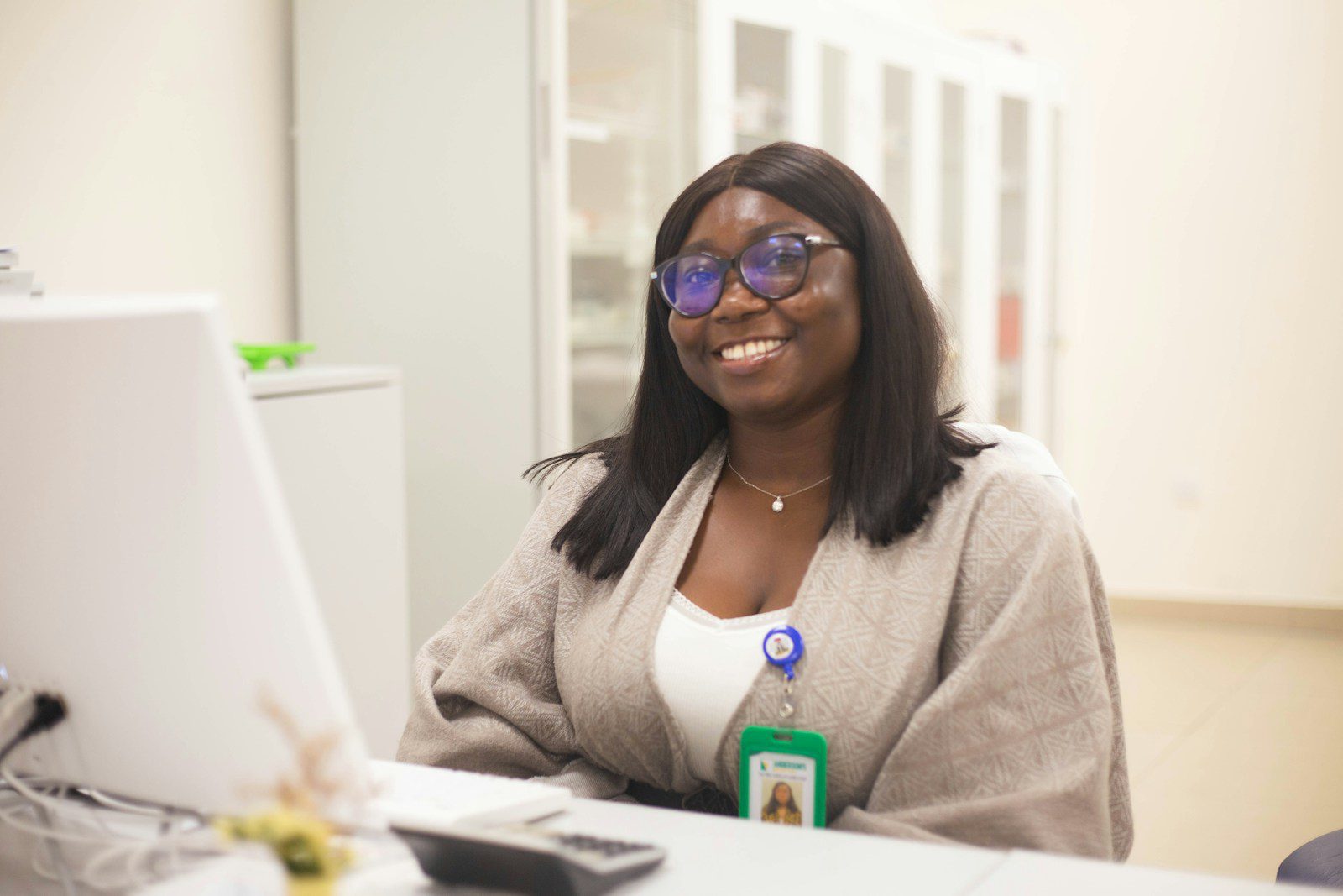 A smiling woman sits behind a desk.
