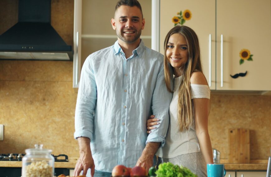 Couple standing in a kitchen with fresh produce.