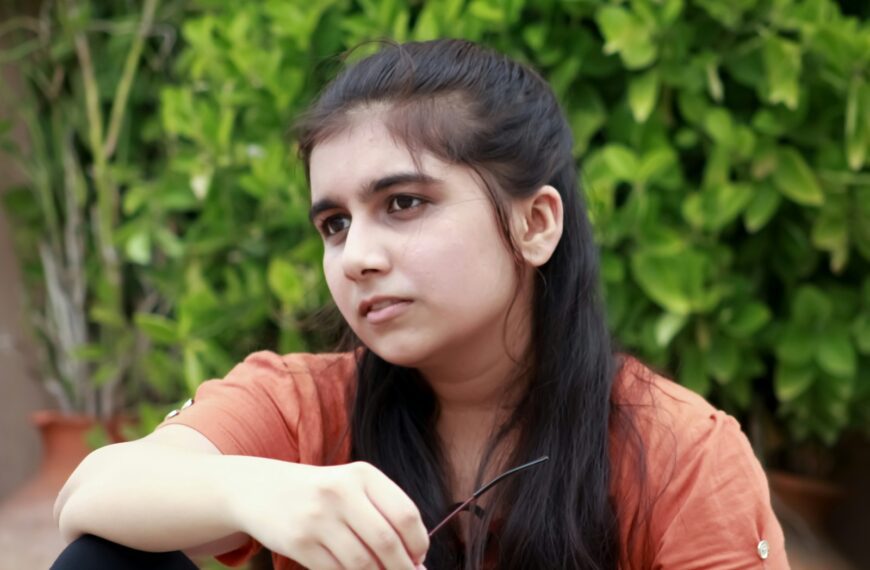 a girl sitting on the ground with her hand on her hip