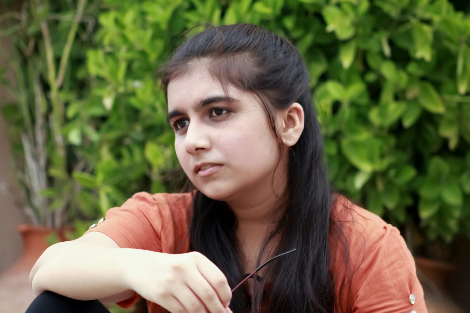 a girl sitting on the ground with her hand on her hip