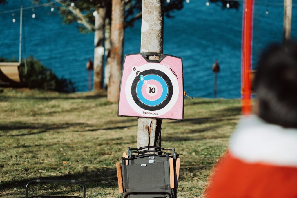 A man standing next to a tree with a target in it