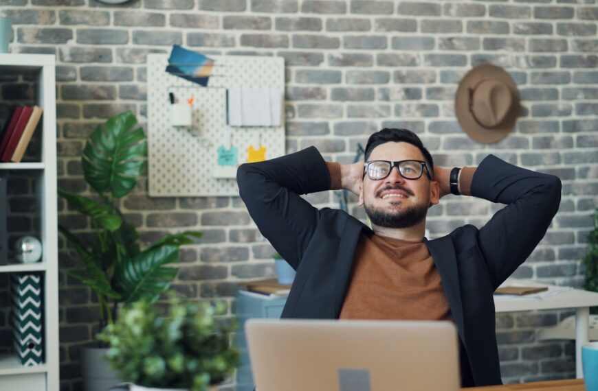 a man sitting at a desk with his hands behind his head