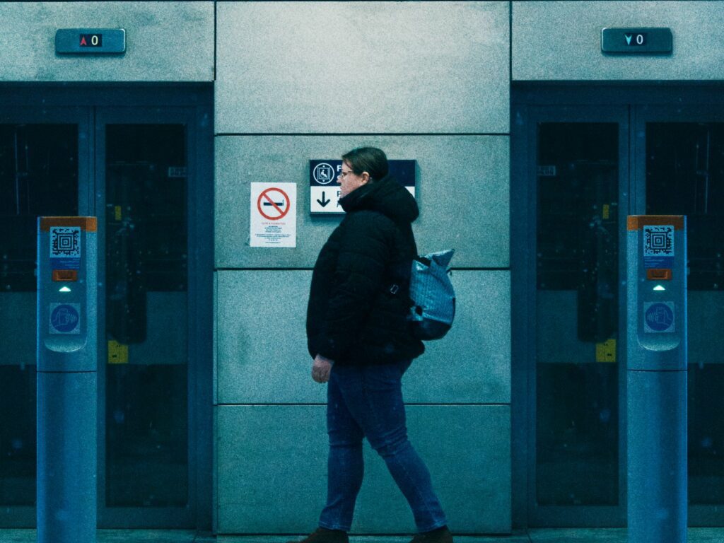 Man walking past subway entrances with backpack