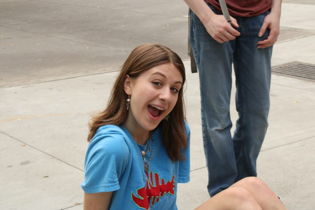 a girl sitting on the ground with a toothbrush in her mouth