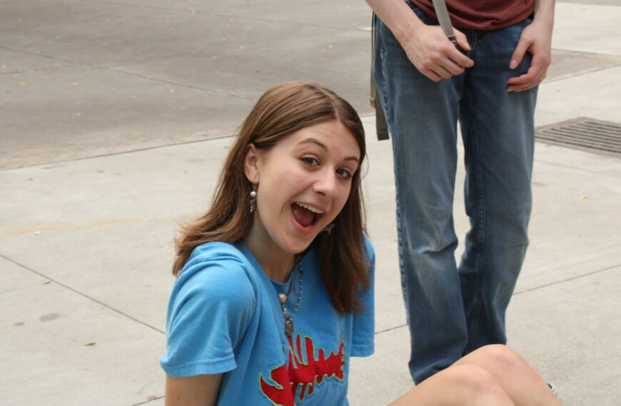 a girl sitting on the ground with a toothbrush in her mouth