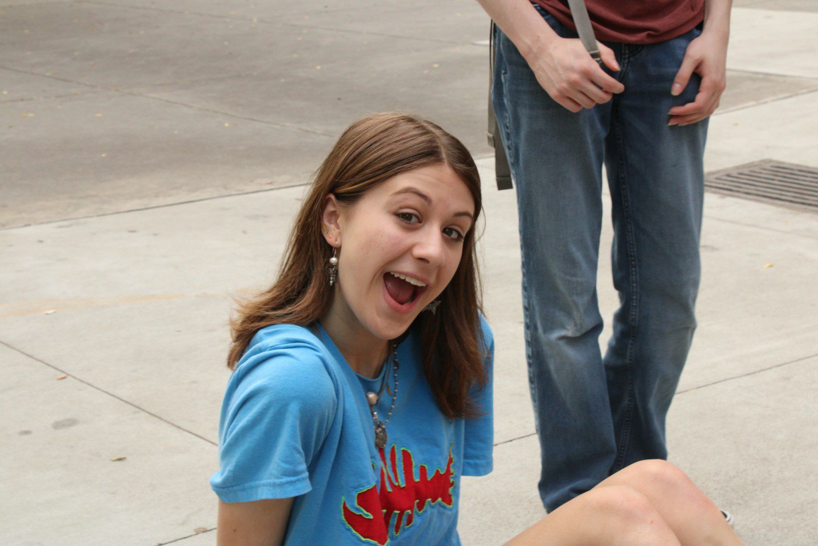 a girl sitting on the ground with a toothbrush in her mouth