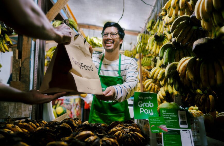 a man holding a paper bag in front of a bunch of bananas
