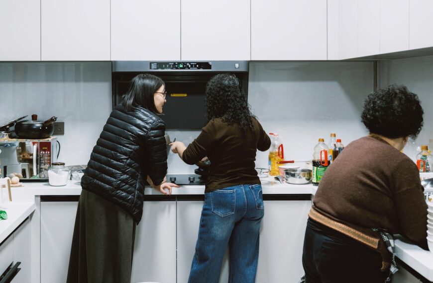 Three people in a modern kitchen preparing food.