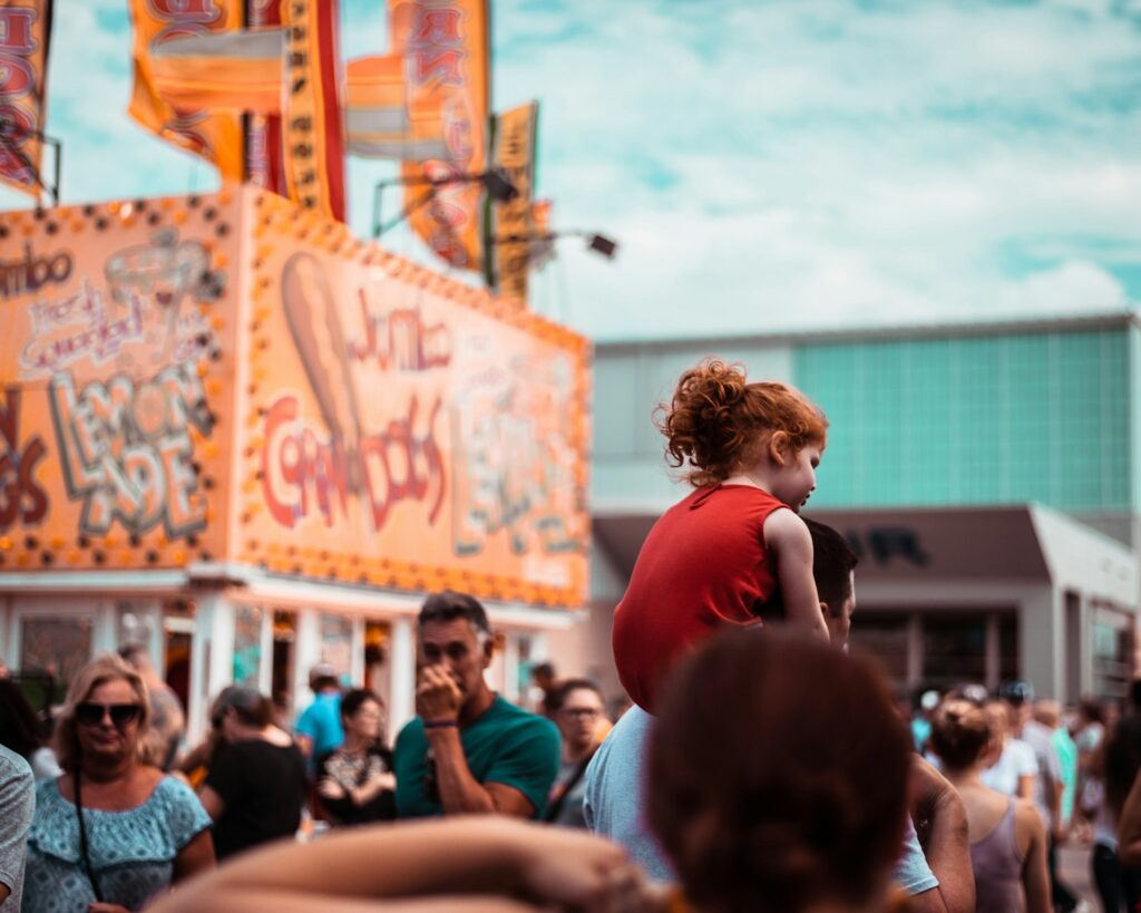 a little girl standing on top of a crowd of people