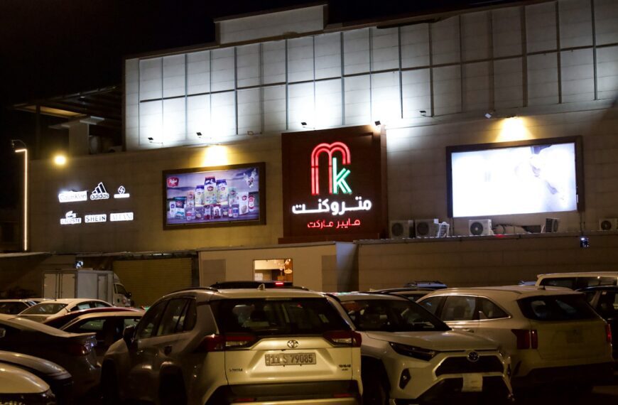 A shopping center at night with lit signs.