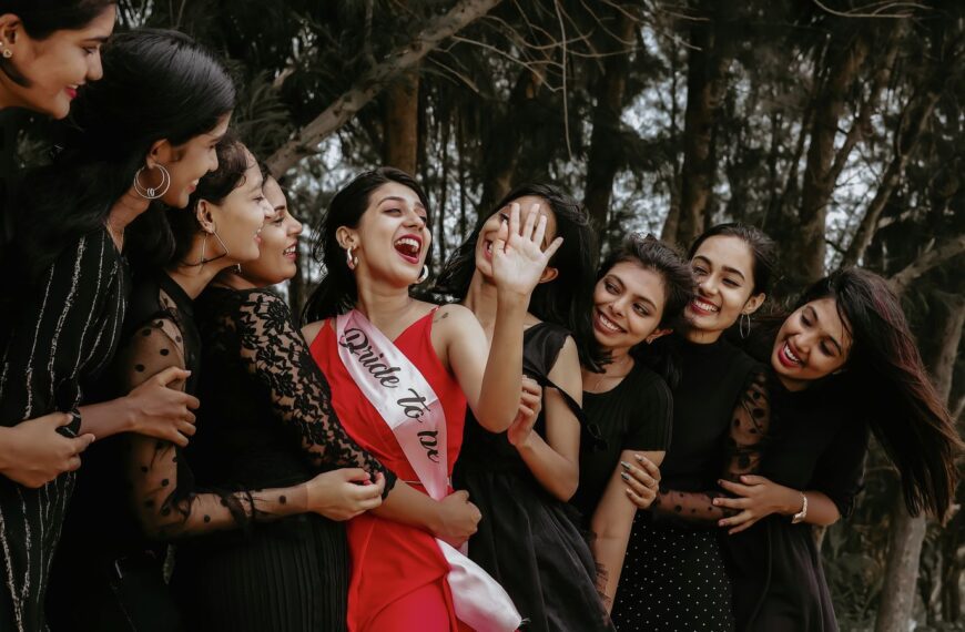 A group of women joyously celebrating outdoors with the bride-to-be wearing a sash.
