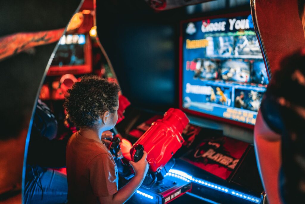 Young child playing an arcade game at an amusement center indoors.