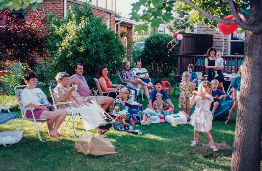 A joyful family gathering outdoors with children playing and adults relaxing in the backyard.
