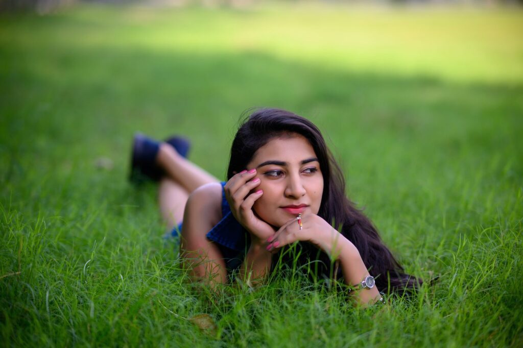 A serene portrait of a woman lying on lush green grass, enjoying a sunny day.