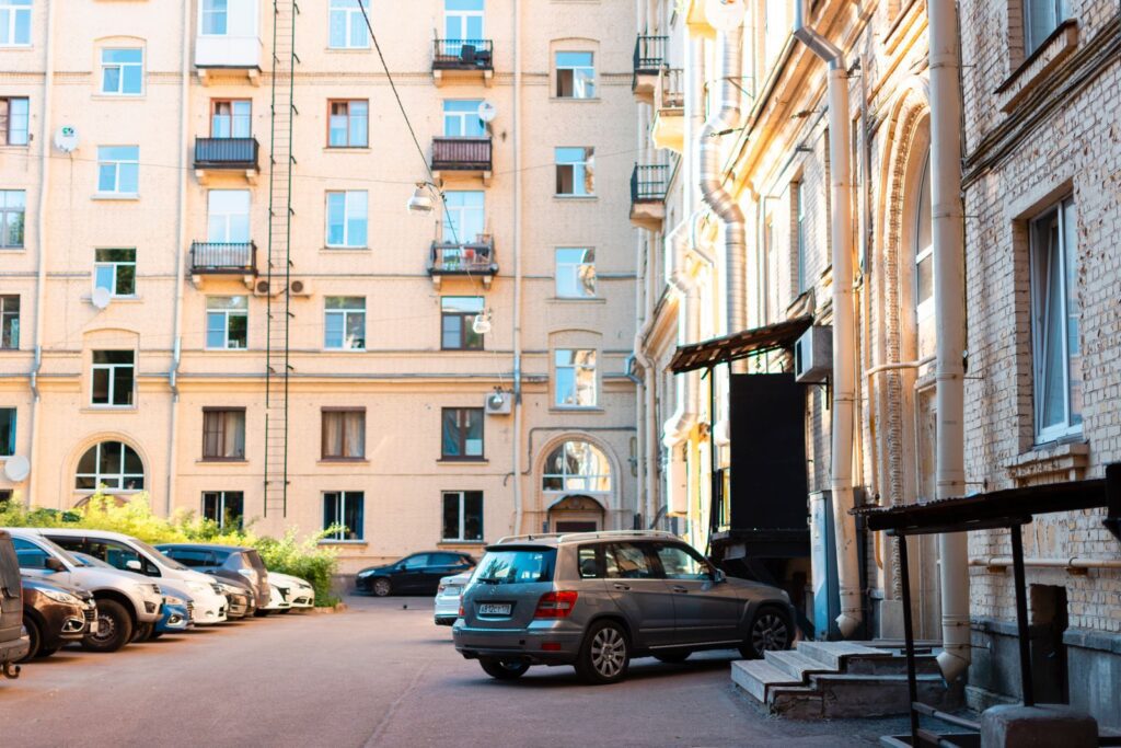 A bright urban courtyard with parked cars and classic apartment buildings in daylight.