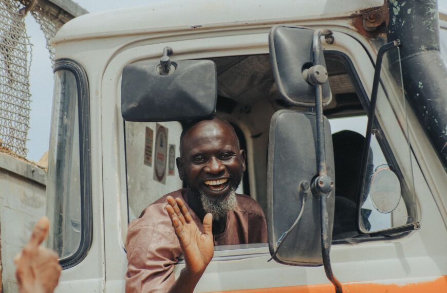 Cheerful truck driver waving and smiling from his vehicle's window.