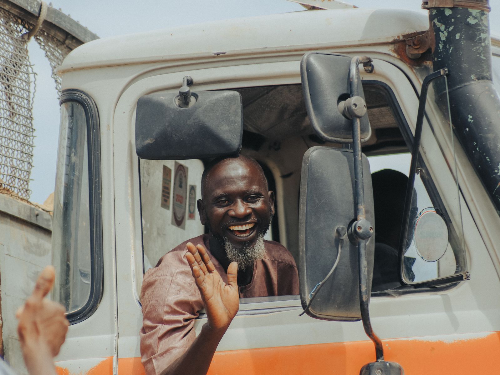Cheerful truck driver waving and smiling from his vehicle's window.