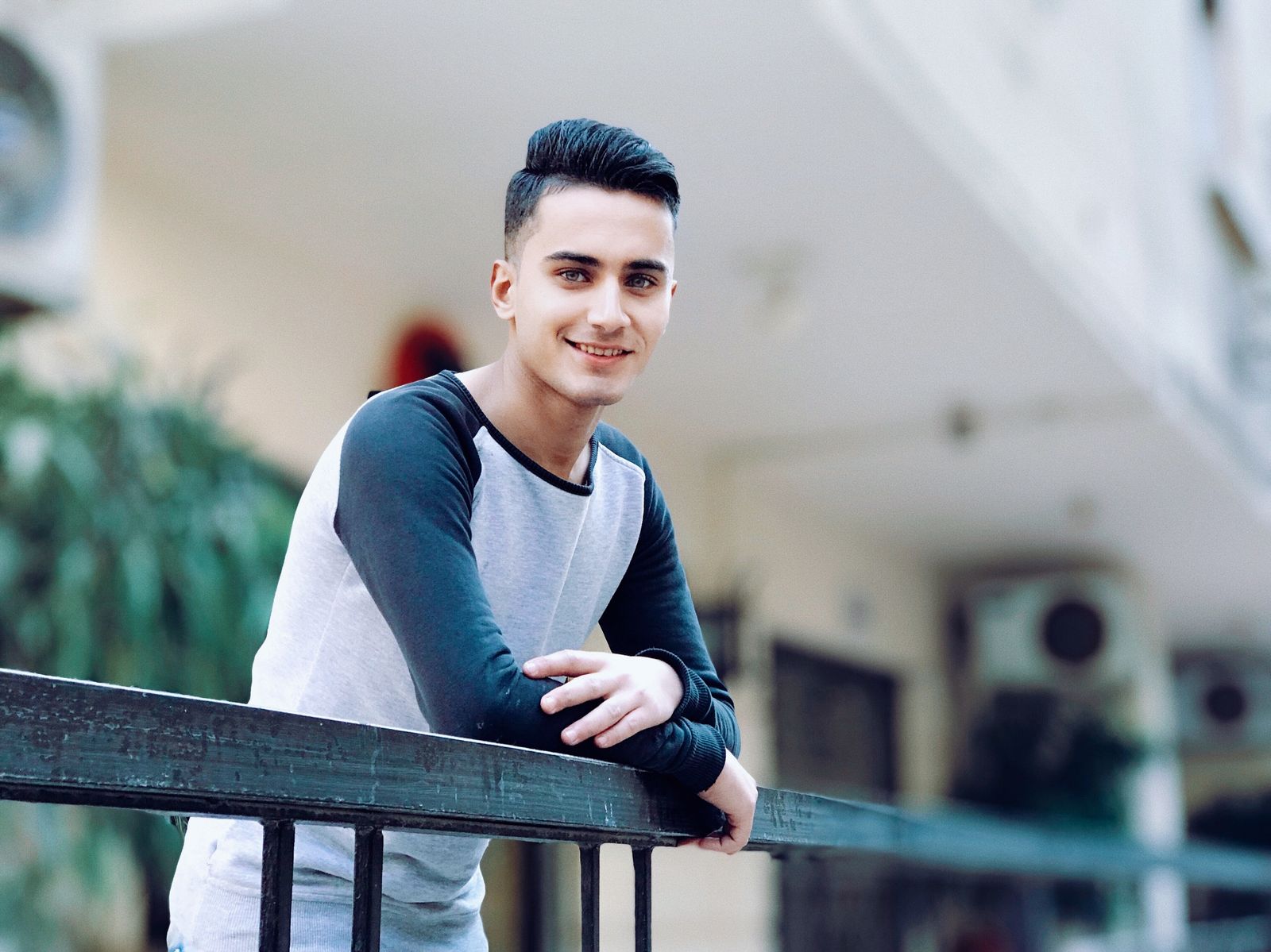 Casual portrait of a smiling young man leaning on a railing outdoors. Happy and relaxed mood.