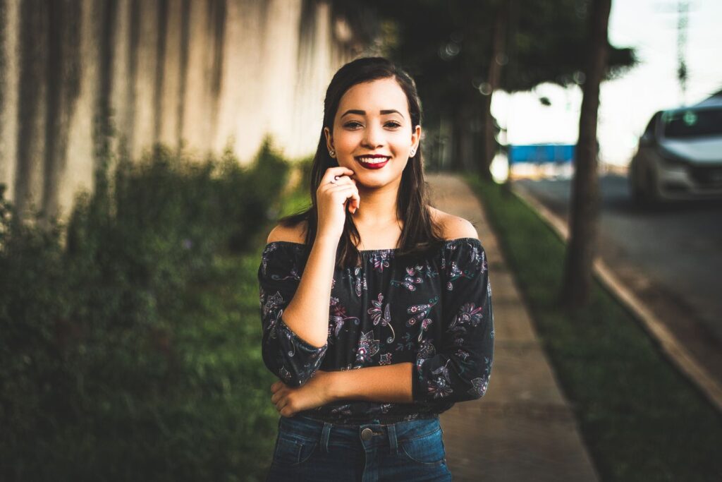 Smiling woman in casual wear posing confidently on a sunny city street.