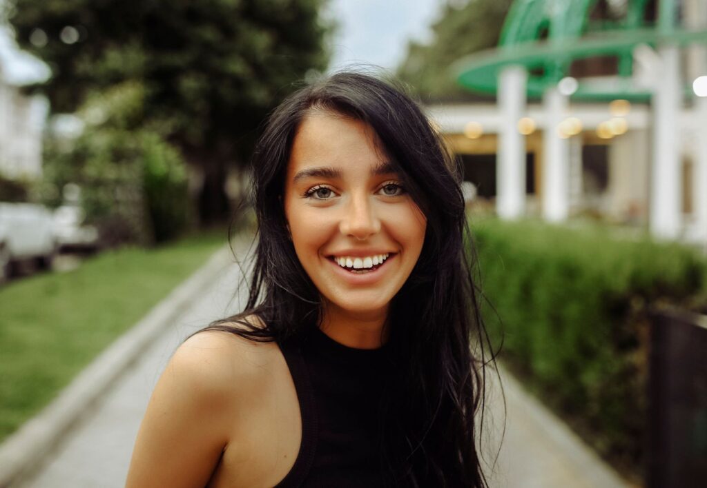 Captivating portrait of a cheerful young woman outdoors in Tbilisi, showcasing natural beauty.
