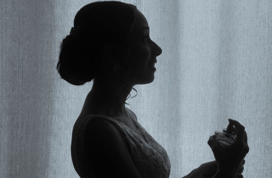 Silhouette of a woman in profile holding a perfume bottle, creating an elegant and intimate mood.