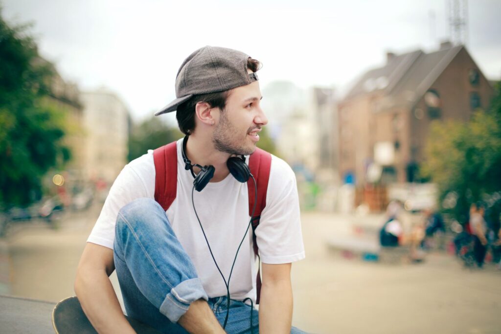 Young man enjoying leisure time outdoors with headphones in a city park.