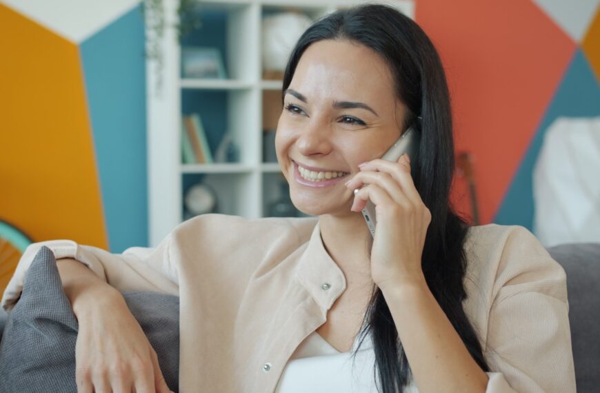 A woman smiling while talking on a cell phone.