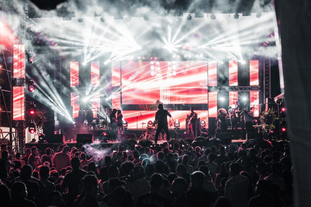 Energetic live music concert featuring performers on a vibrant stage, captivating a large audience.