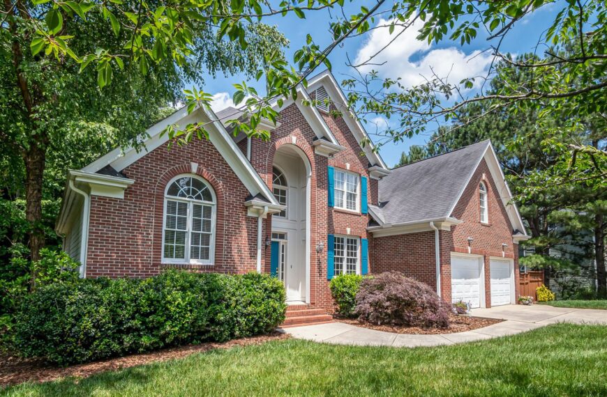 Beautiful brick suburban house surrounded by lush greenery, showcasing classic architecture.