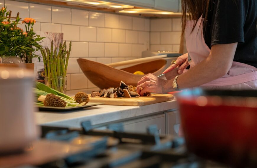 a woman in a kitchen chopping vegetables on a cutting board